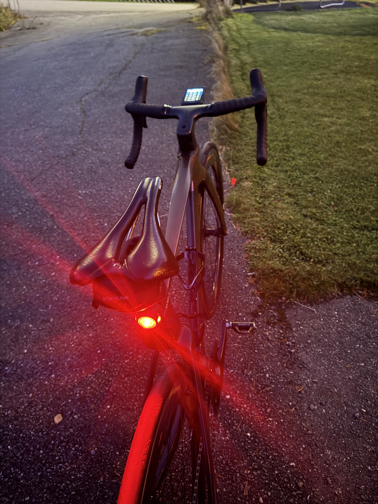 Merida Reacto 8000 bakfra i skumringen med Garmin Varia RTL516 under salen, Garmin Edge 1050 på stemet og det røde baklyset tent